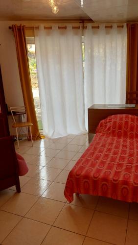 - une chambre avec un lit rouge et des rideaux blancs dans l'établissement Mihechris, à Collioure