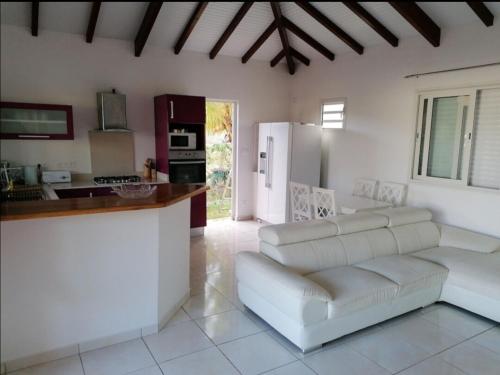 Una sala de estar con un sofá blanco y una cocina. en Villa Bien-Désiré, en Saint-François