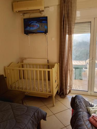a bedroom with a crib and a tv on the wall at family in Kardítsa