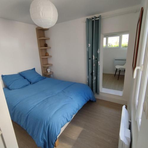 une chambre avec un lit bleu et un miroir dans l'établissement Petite maison bord de mer, à Langrune-sur-Mer
