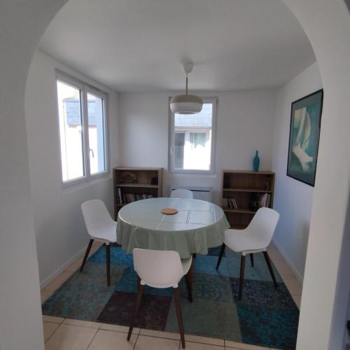 une salle à manger avec une table et des chaises blanches dans l'établissement Petite maison bord de mer, à Langrune-sur-Mer