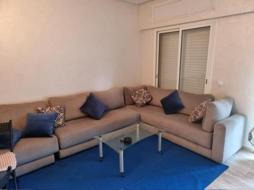 a living room with a brown couch with blue pillows at Al Jazeera beach in Zaouia Sidi Rahkal