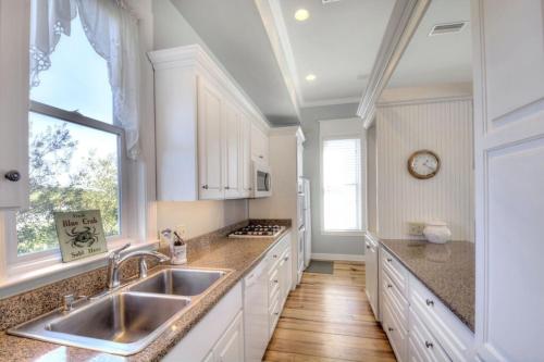 una cucina con mobili bianchi, un lavandino e una finestra di Centennial Coast Cottage - with Heated pool a Saint Simons Island