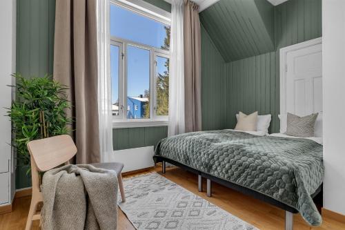 une chambre verte avec un lit et une fenêtre dans l'établissement Lovely city center apartment with amazing views and free parking!, à Tromsø