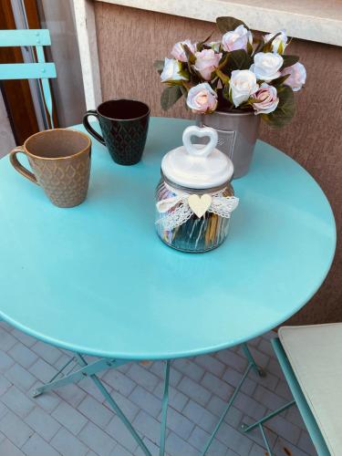 a blue table with a pot of flowers and two cups at Camera luminosa per viaggiatori in Conegliano