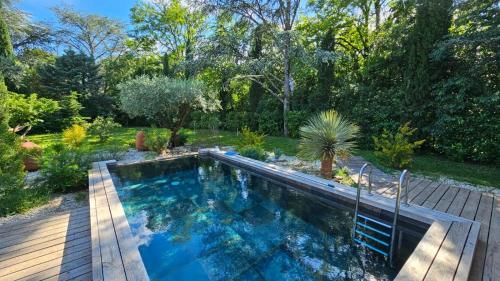 une piscine dans un jardin avec une terrasse en bois dans l'établissement VILLA Nîmes tourmagne PISCINE, à Nîmes