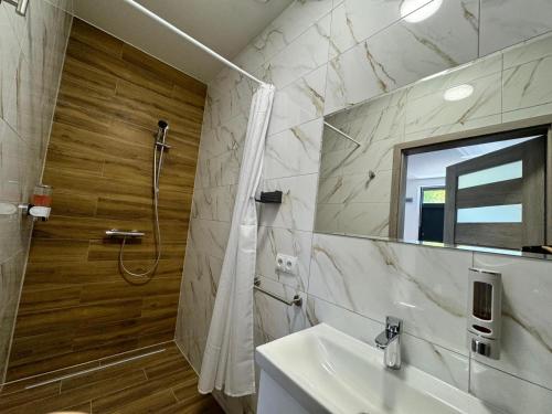 ein Badezimmer mit Dusche, Waschbecken und Spiegel in der Unterkunft Słoneczne pokoje nad jeziorem Nyskim in Skorochow