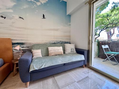 - un canapé dans le salon orné d'une peinture murale dans l'établissement Studio Baie des Anges à deux pas de la mer, à Villeneuve-Loubet