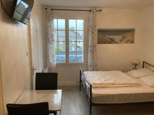 a bedroom with a bed and a table and a window at Un cocon en bord de mer in La Terre du Pont
