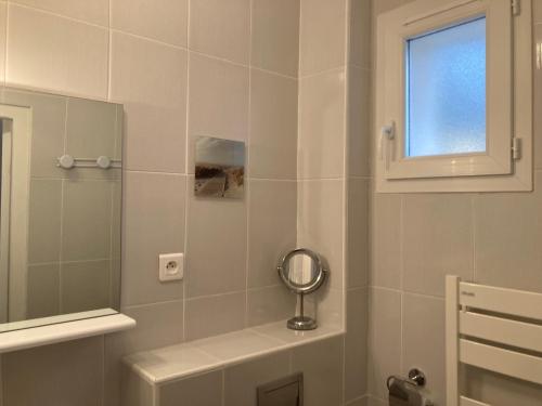 une salle de bain avec un miroir et un lavabo dans l'établissement Un cocon en bord de mer, à La Terre du Pont