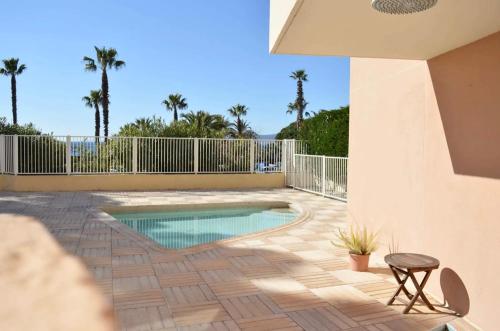 une piscine sur un patio avec des palmiers dans l'établissement Charmant studio en front de mer avec balcon, à Saint-Raphaël