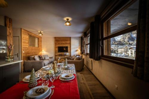 un salon avec une table et un tissu de table rouge dans l'établissement Les Chalets D'adrien - 4 pièces 8 personnes exposé Ouest MAE-7954, à Valloire