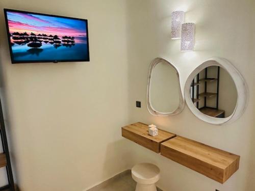 a bathroom with a tv on the wall and a mirror at Memories in Ornos