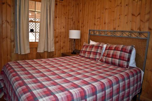 1 dormitorio con 1 cama con manta a cuadros y ventana en Elk - by The Chalets, en South Bloomingville