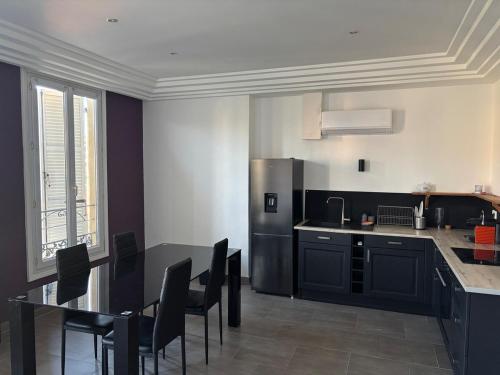 une cuisine avec des armoires noires, une table et des chaises dans l'établissement 3-R bright, beach within 15 min walk, à Nice