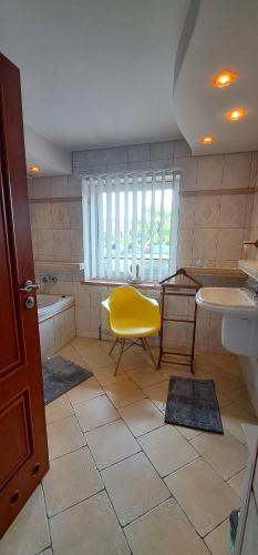a bathroom with a yellow chair and a tub and sink at Złoty Trakt pokoje i rowery in Złoty Stok