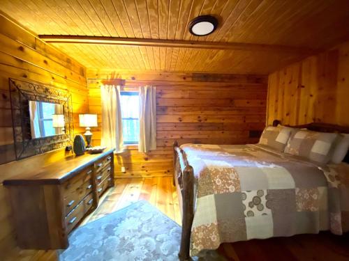 a bedroom in a log cabin with a bed and a desk at Oakridge - by The Chalets in South Bloomingville