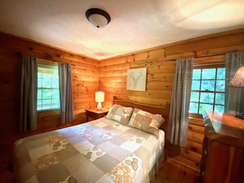 a bedroom with a bed in a room with wooden walls at Pioneer - by The Chalets in South Bloomingville