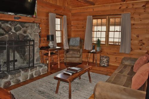 a living room with a fireplace in a log cabin at Timber Ridge - by The Chalets in South Bloomingville