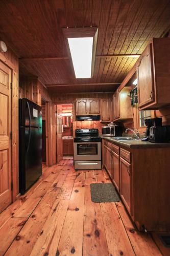 a kitchen with wooden floors and a kitchen with a black refrigerator at Timber Ridge - by The Chalets in South Bloomingville