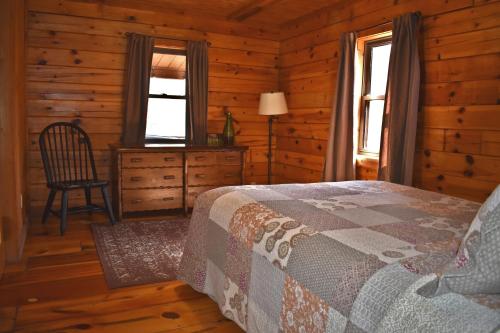 a bedroom with a bed and a chair in a cabin at Sycamore - by The Chalets in South Bloomingville