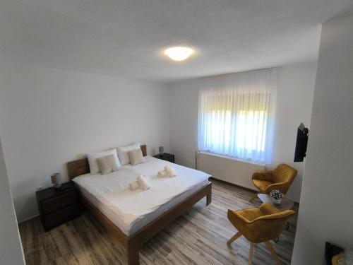 a white bedroom with a bed and a chair at House Mila in Korenica