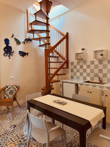 a kitchen with a table and a spiral staircase at Favignana in centro con terrazza in Favignana