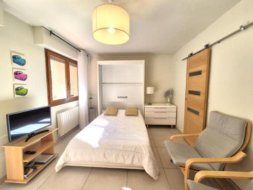 une chambre avec un lit, une télévision et une chaise dans l'établissement Résidence Le Saint Charles A - Agréable et lumineux studio à 50m des Thermes Chevalley ! MAE-7754, à Aix-les-Bains