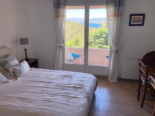 une chambre avec un lit et une grande fenêtre dans l'établissement La Madrague du Petit Prince vue mer époustouflante et jardin, à Saint-Cyr-sur-Mer