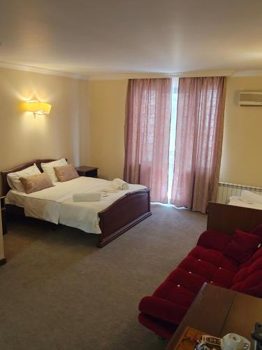 a bedroom with a bed and a red couch at Ritsa Boutique Hotel in Batumi