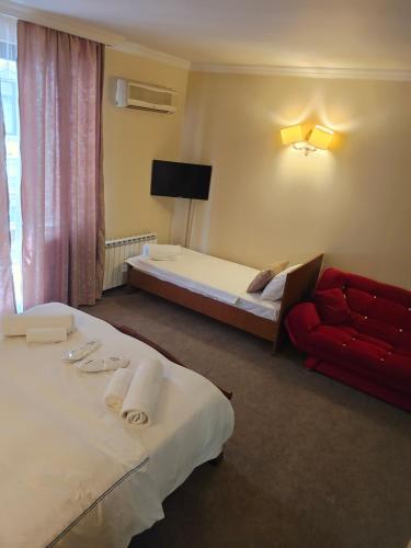 a hotel room with two beds and a red couch at Ritsa Boutique Hotel in Batumi