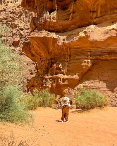 a boy standing in the desert near a cliff at Talal Rum Luxury Camp in Jurf ad Darāwīsh