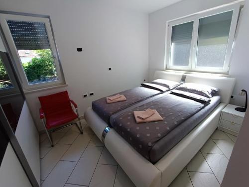 a bedroom with a bed and a red chair at Heart of Strunjan Apartments AL in Strunjan