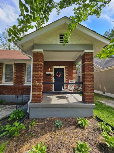 a brick house with a front porch with a chair at Cool and calm place to live in Memphis