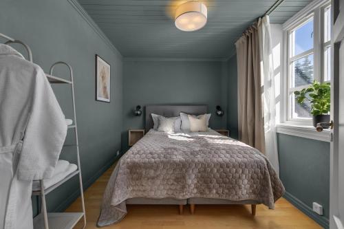 una camera da letto blu con un letto e una finestra di Stylish City Apartment With Mountain View a Tromsø