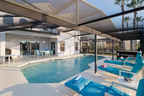 a swimming pool with blue chairs and a house at Sunny South Facing Pool with Hot Tub and Lake View Near Disney in Kissimmee