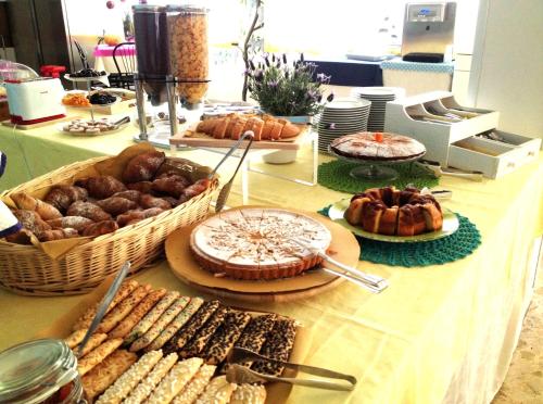 uma mesa com diferentes tipos de pão e pastelaria em Hotel Lux em Cesenatico