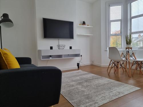a living room with a flat screen tv on a wall at Bright East Dulwich Apartment in London