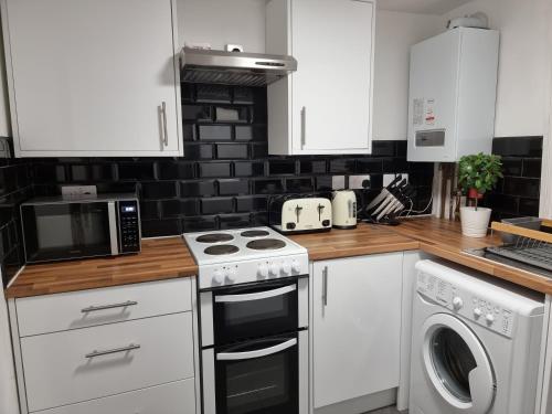 a kitchen with white cabinets and a stove top oven at Bright East Dulwich Apartment in London