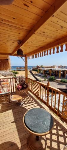 a wooden deck with a table and a hammock at Green Beach Camp & Hotel in Nuweiba