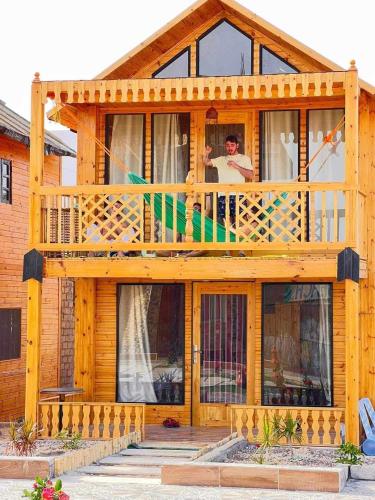 a man sitting on the balcony of a wooden house at Green Beach Camp & Hotel in Nuweiba
