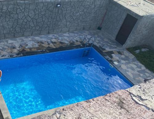 a swimming pool with blue water in a stone wall at Дом с бассейном в Ереване in Aghk'ilisa