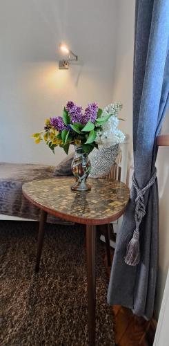 a vase of purple flowers sitting on a table at Złoty Trakt pokoje i rowery in Złoty Stok