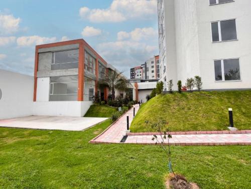 a building with a grassy yard next to a building at Departamento ideal para trabajo o turismo, cerca de Embajada A, Solca y Estadio O in Quito