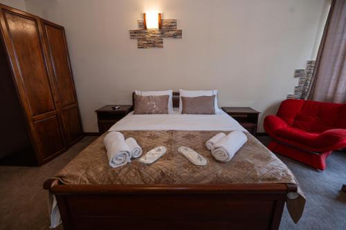 a bedroom with a bed with towels and a red chair at Ritsa Boutique Hotel in Batumi