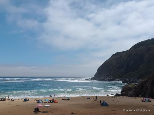 a group of people on a beach near the ocean at Hostal Vista hermosa del Páramo alto, Laguna Verde in Valparaíso