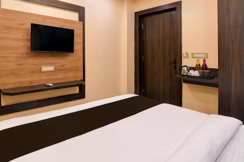 a hotel room with a bed and a flat screen tv at Super Townhouse OAK Bulbuli Neer in Kolkata
