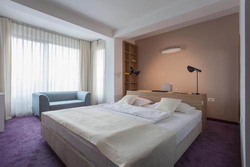 a bedroom with a large bed and a blue chair at City Park Hotel in Skopje