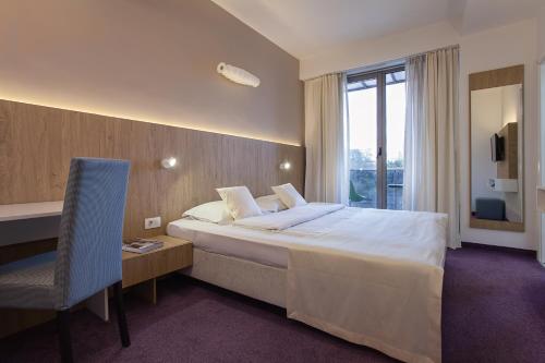 a hotel room with a bed and a desk and a window at City Park Hotel in Skopje