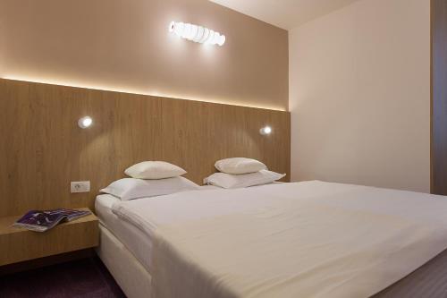 a bedroom with a large bed with white sheets and pillows at City Park Hotel in Skopje